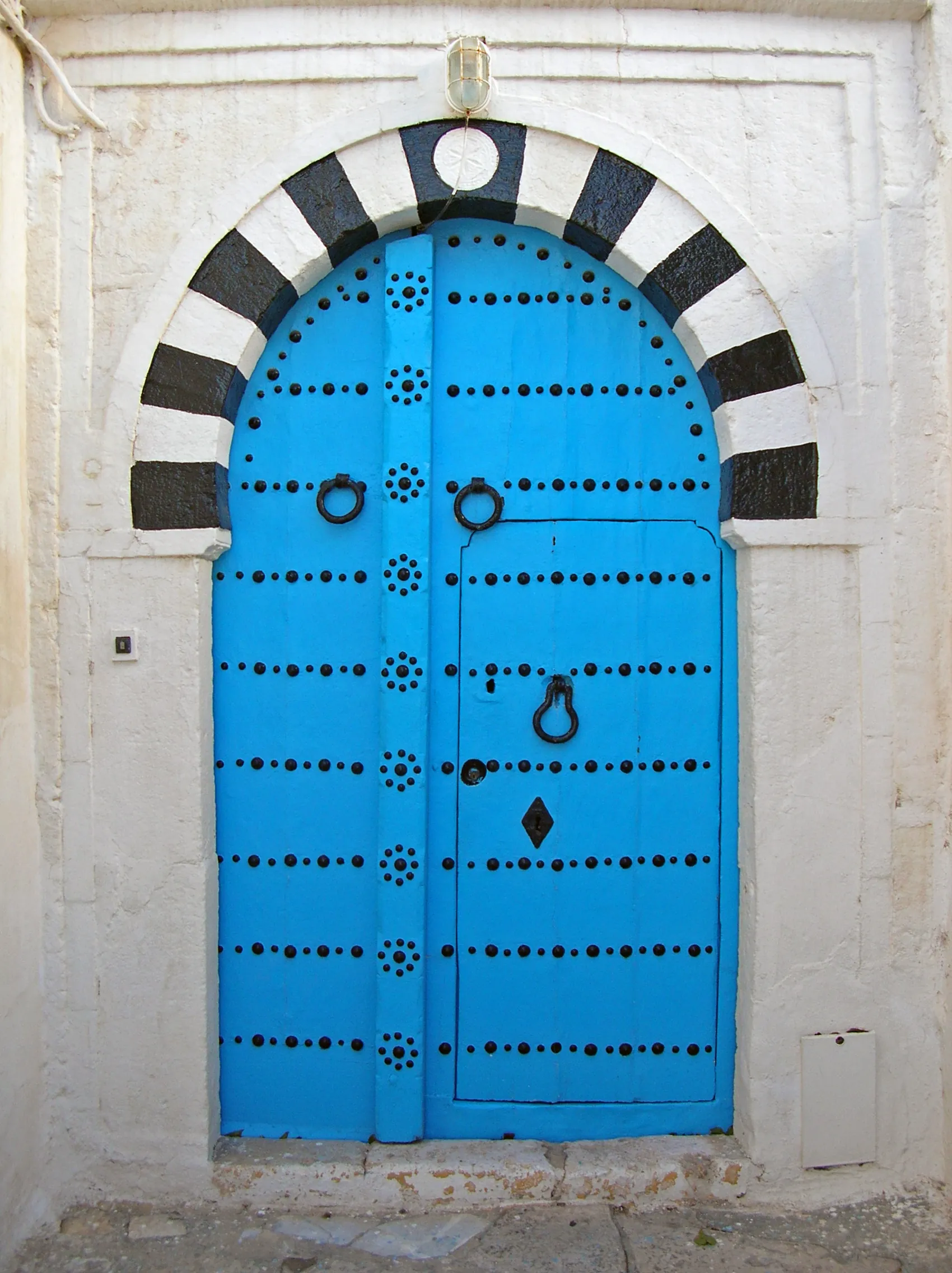 Porte bleue cloutée et arche mauresque de Sidi Bou Saïd
